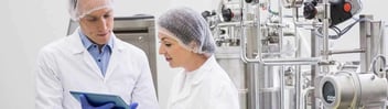 Auditors wearing hair nets looking at tablet screen in food factory